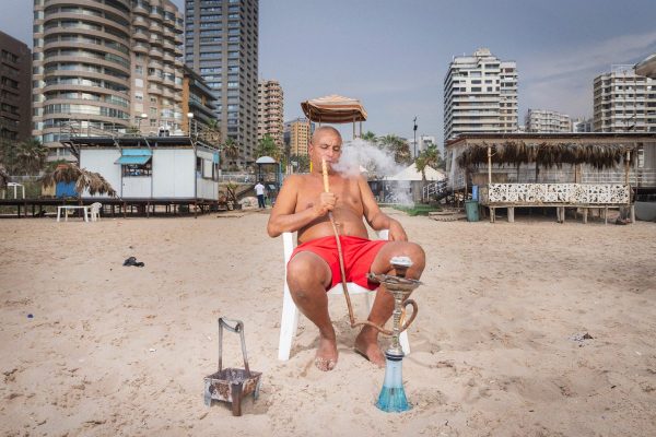 Fadi Farran smokes shisha on the beach of Ramlet el-Baida, in the south of Beirut, echoed by the constant buzz of Israeli drones. For years he has worked as an employee in one of the beach resorts, but since the war reached Beirut, instead of holidaymakers, he has started to deal with the thousands of displaced people who have fled the south, having nowhere else to."Even if my work has changed, its purpose is similar: it is to give a moment of rest to those who have none. And these families have lost everything"
